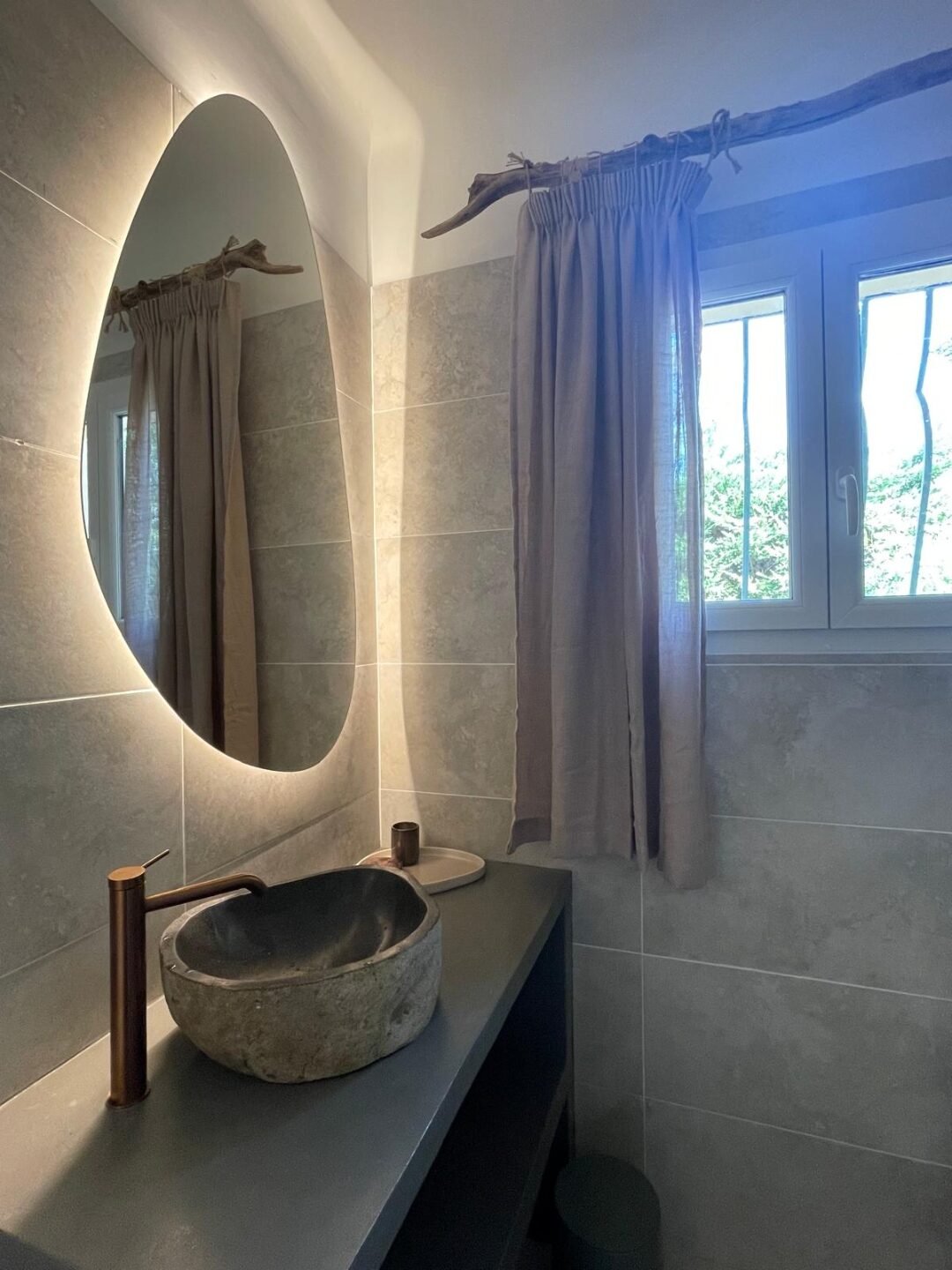 Badezimmer mit Steinwaschbecken und Leinenvorhang