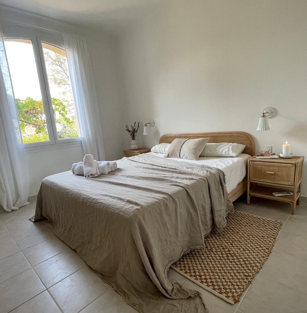 Schlafzimmer mit Rattan-Kopfteil und rundbogigem Fenster