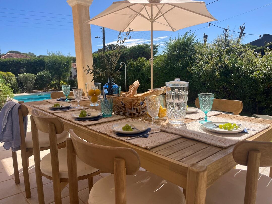 Gedeckter Esstisch unter der Pergola mit Blick auf den Pool